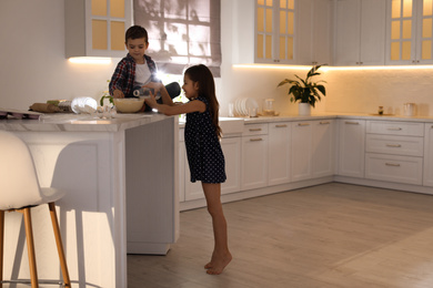 Photo of Cute little children cooking dough in kitchen at home