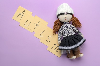 Photo of Notes with word "Autism" and doll on color background