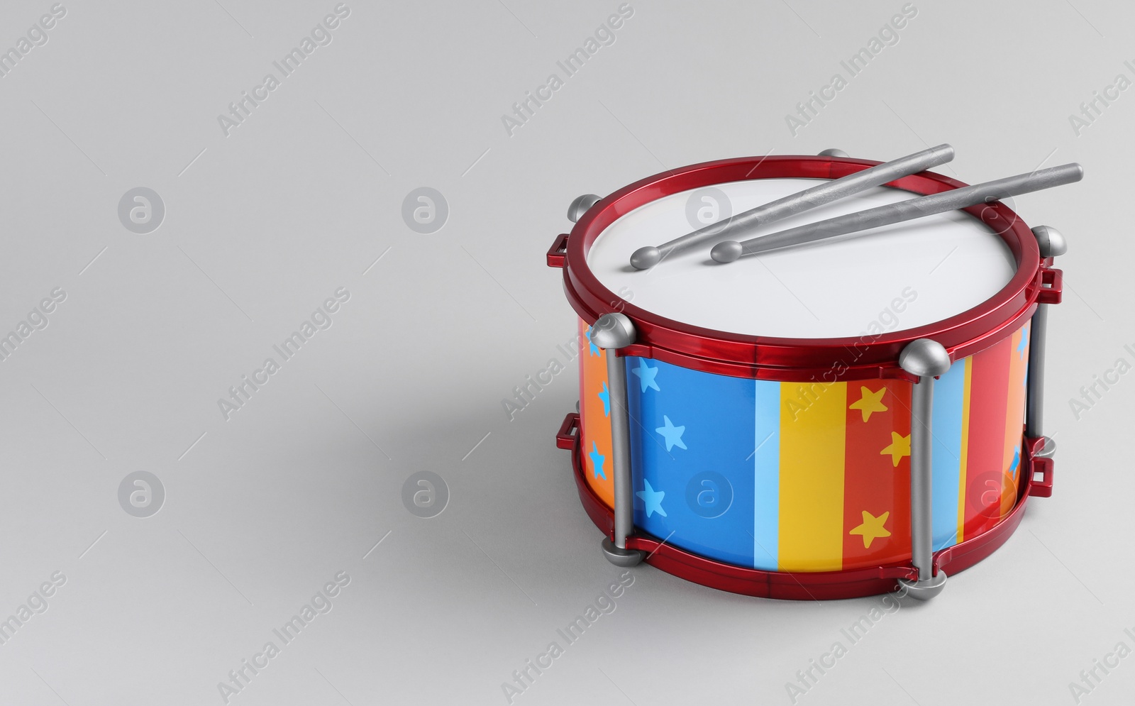 Photo of Colorful drum and sticks on light background. Percussion musical instrument