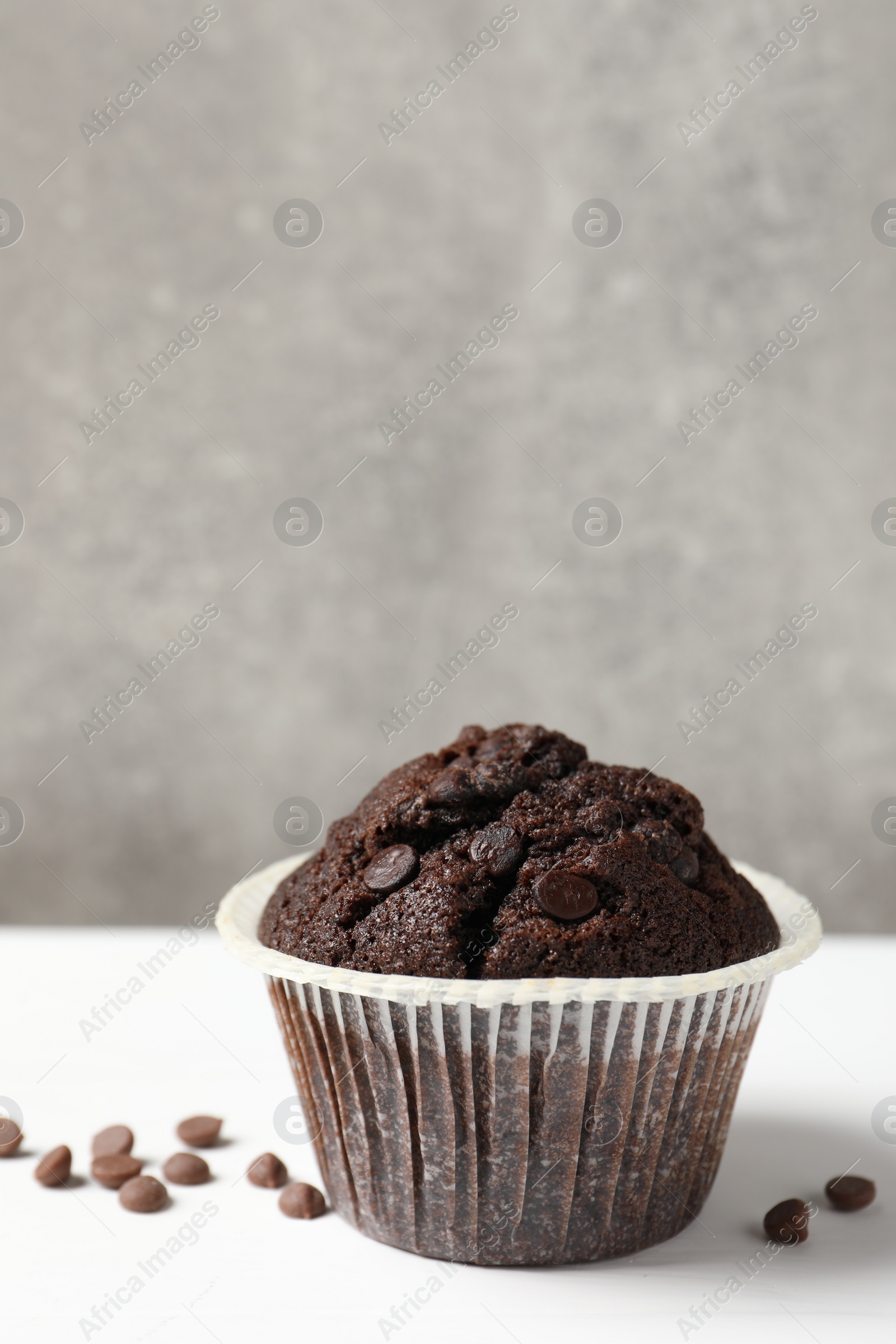 Photo of Tasty chocolate muffin on white table, space for text