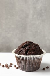 Tasty chocolate muffin on white table, space for text