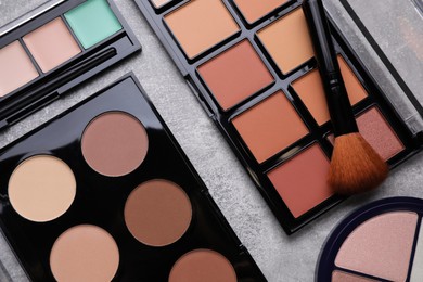 Different contouring palettes and brush on light gray background, flat lay. Professional cosmetic product
