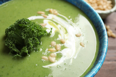 Tasty kale soup with pine nuts on table, closeup