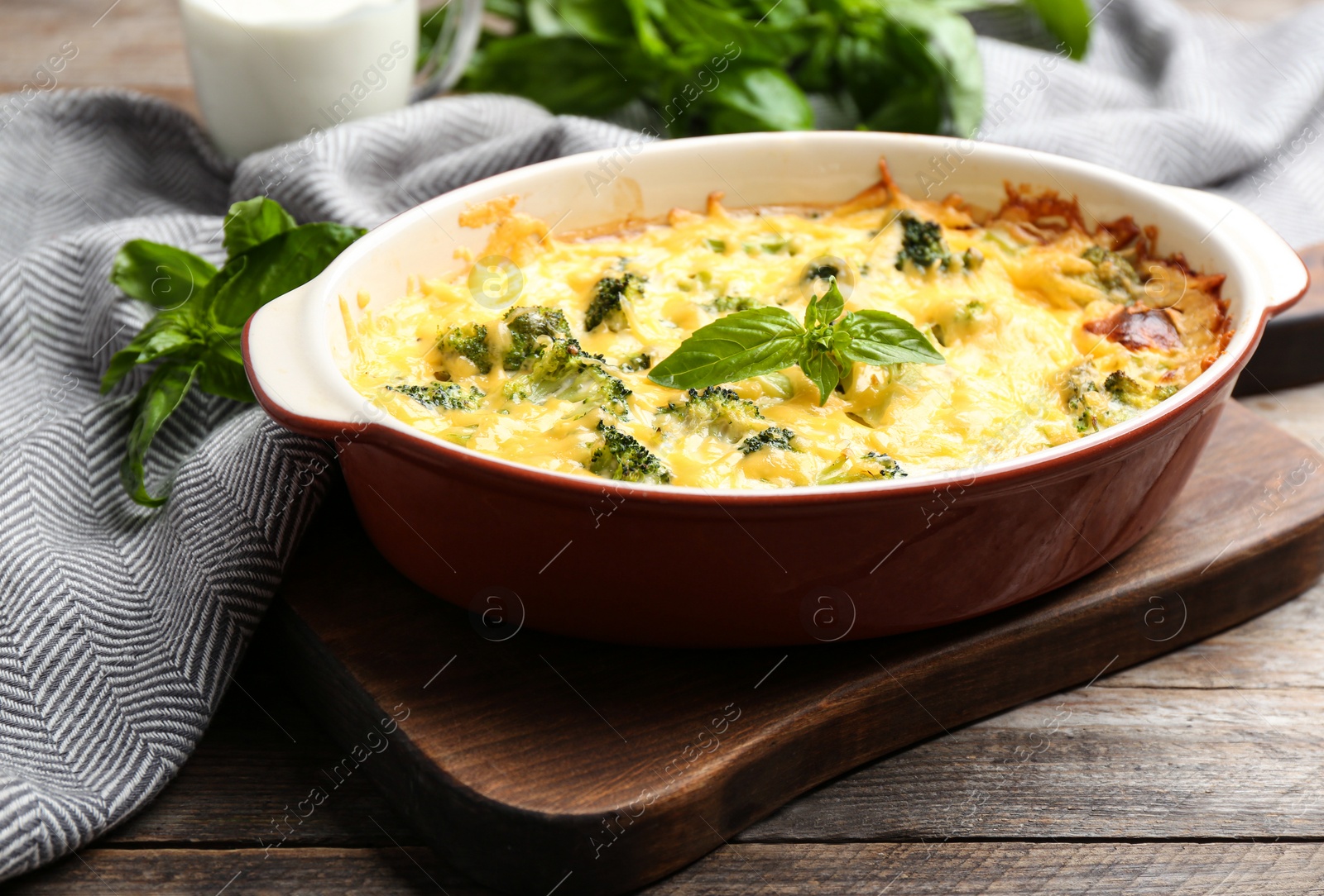 Photo of Tasty broccoli casserole in baking dish on wooden table