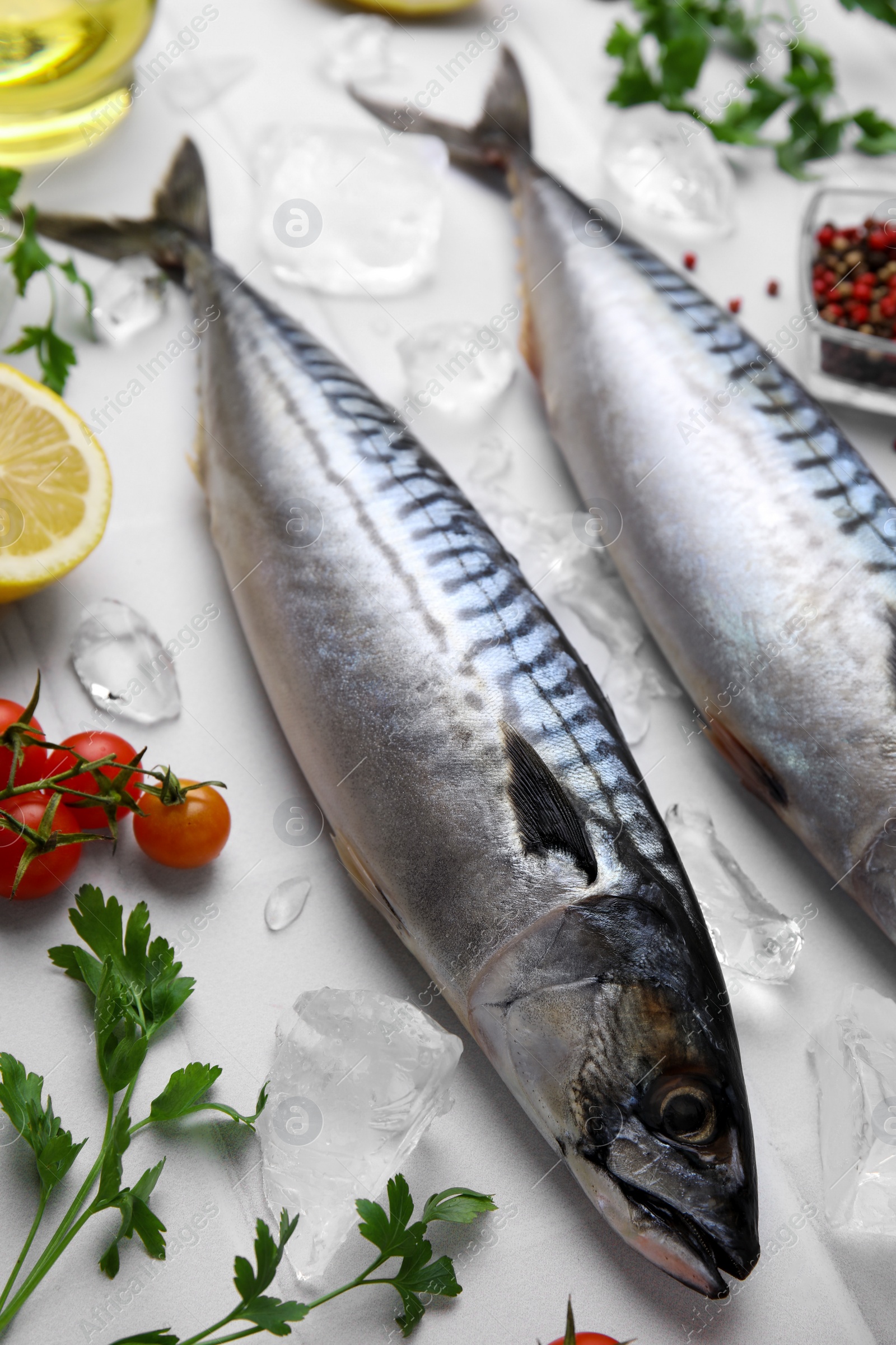 Photo of Raw mackerel, tomatoes and parsley on white table, above view