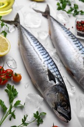 Photo of Raw mackerel, tomatoes and parsley on white table, above view