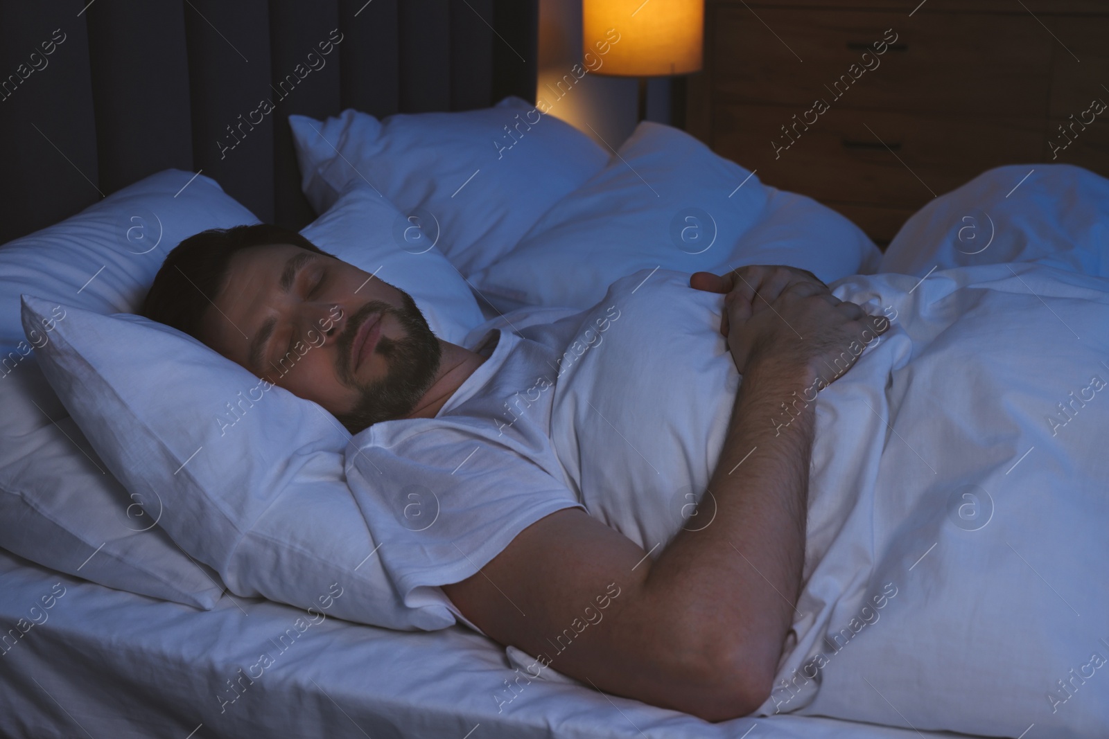 Photo of Handsome man sleeping in bed at night