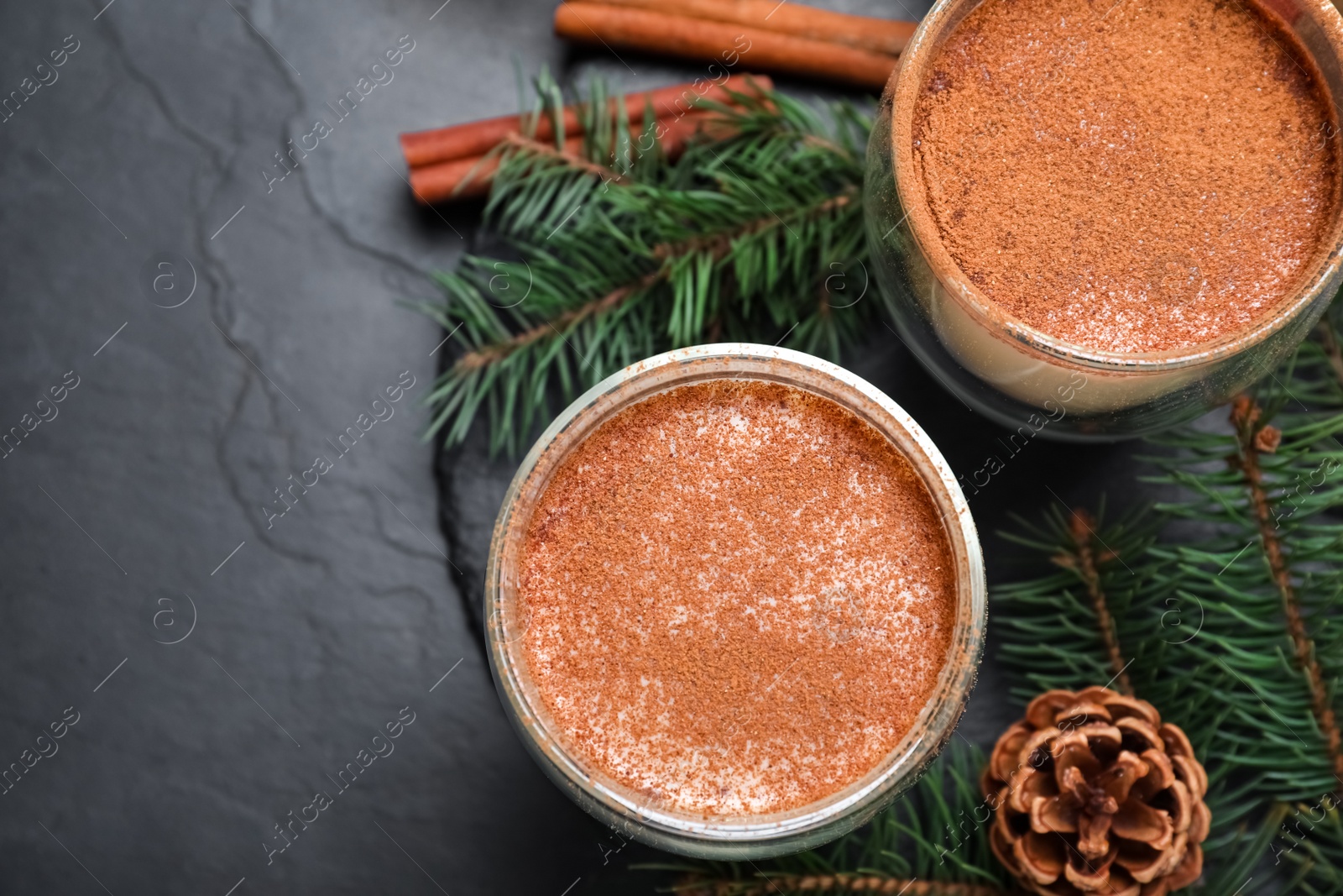 Photo of Delicious Christmas cocktail with liqueur on black table, flat lay