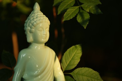Decorative Buddha statue under tree branch outdoors. Space for text