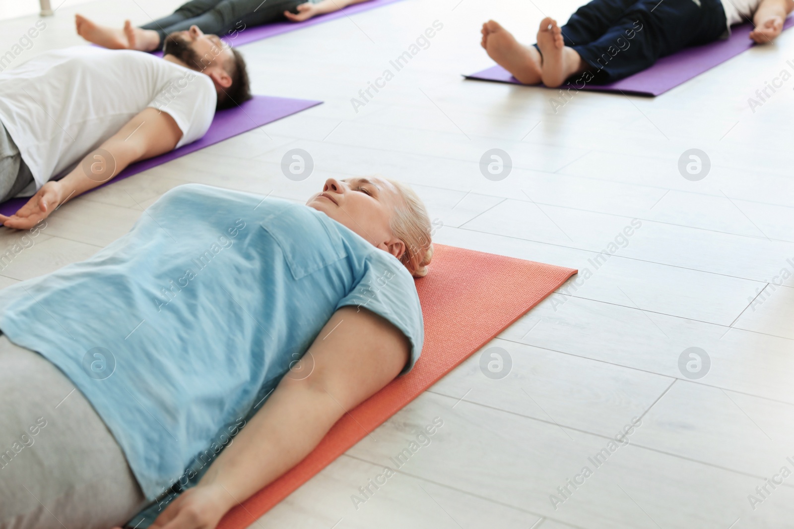 Photo of Group of people in sportswear practicing yoga indoors