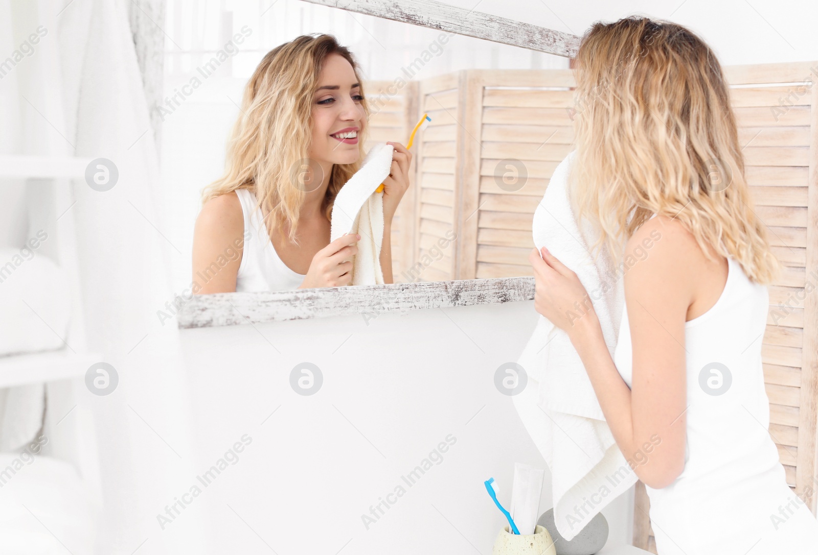 Photo of Young woman with toothbrush and towel in bathroom