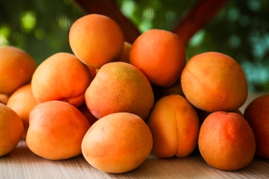 Heap of delicious ripe apricots on wooden table outdoors, closeup
