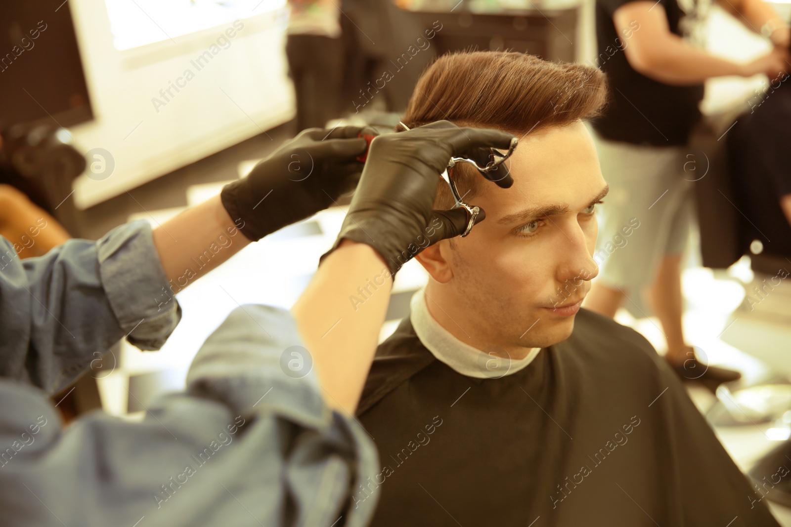 Image of Professional barber working with client in hairdressing salon