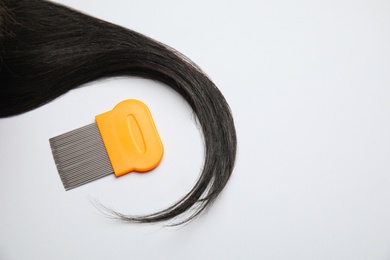 Photo of Strand of dark hair with lice comb on white background, top view