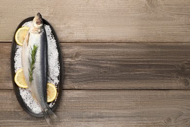 Photo of Plate with salted herring, rosemary and lemon on wooden table, top view. Space for text