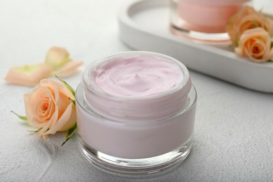 Photo of Jar of organic cream and roses on white table