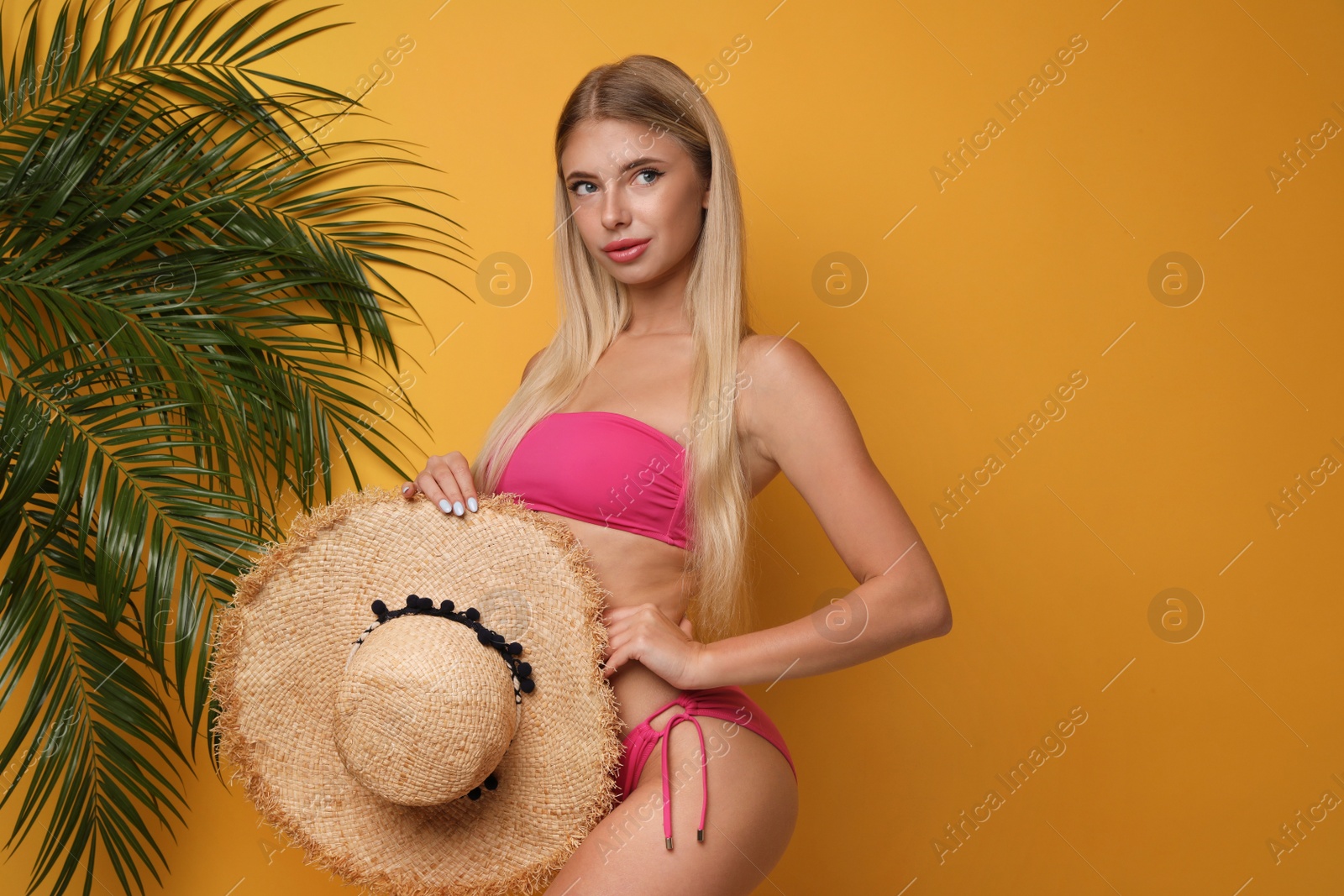 Photo of Pretty young woman wearing stylish bikini on orange background