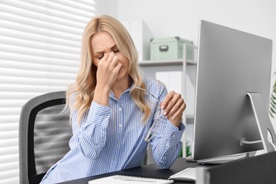 Overwhelmed woman with glasses at table in office