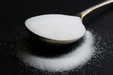 Photo of Spoon with salt on black background, closeup