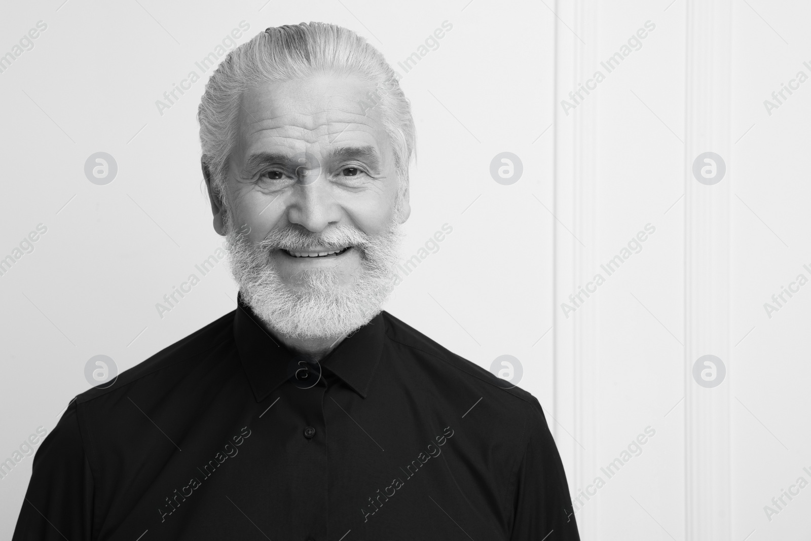 Image of Portrait of handsome senior man against light wall, space for text. Black and white effect