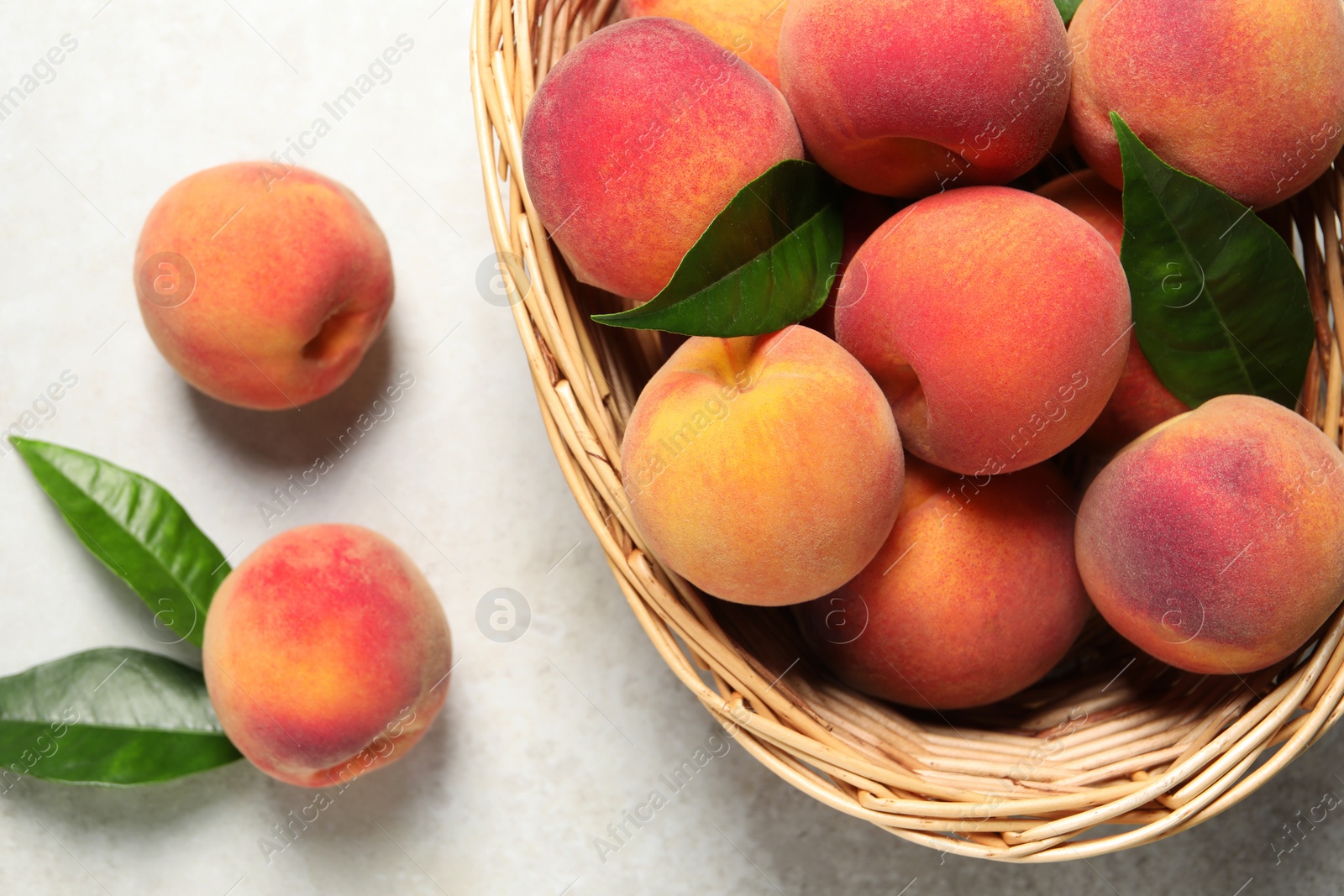 Photo of Fresh peaches and leaves on light textured table, flat lay