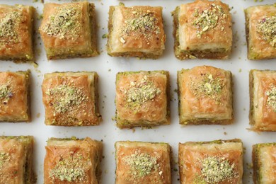 Photo of Delicious fresh baklava with chopped nuts on white table, flat lay. Eastern sweets