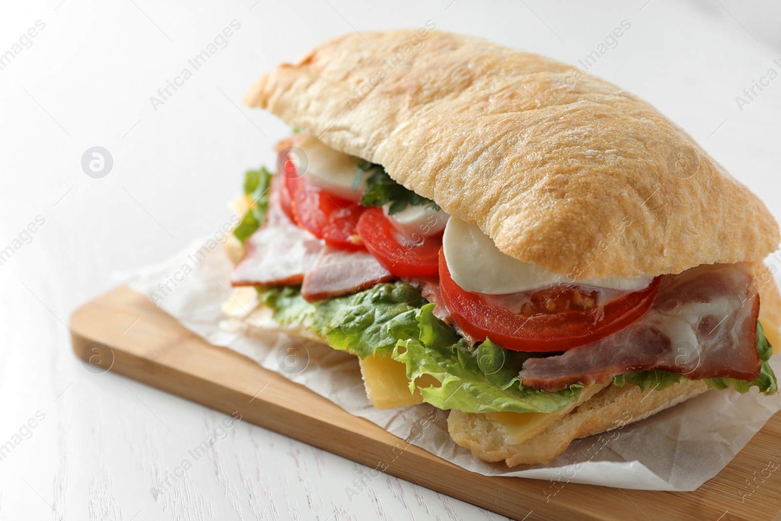 Photo of Delicious sandwich with fresh vegetables and mozzarella on white table, closeup