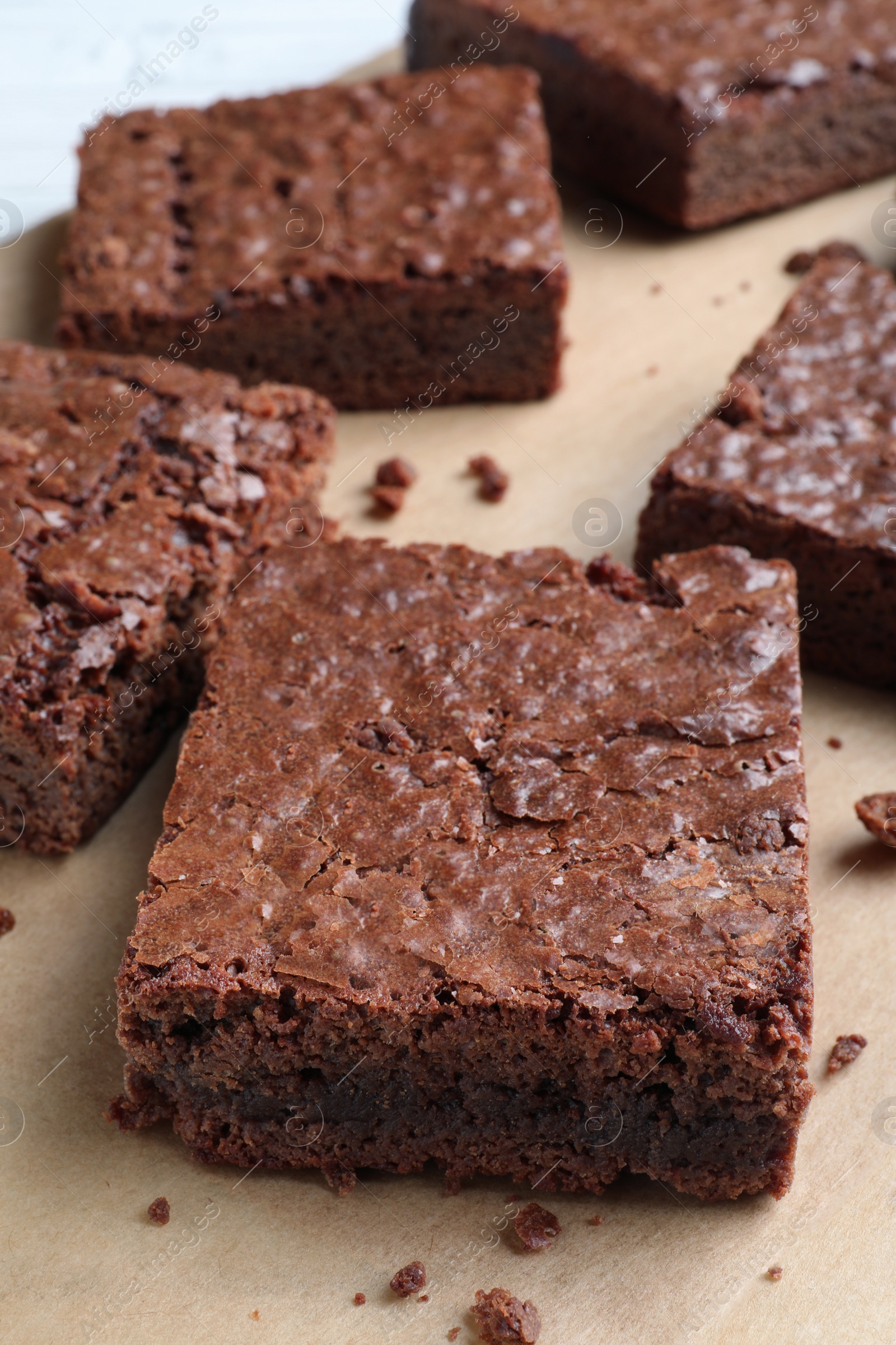 Photo of Delicious chocolate brownies on parchment paper, closeup