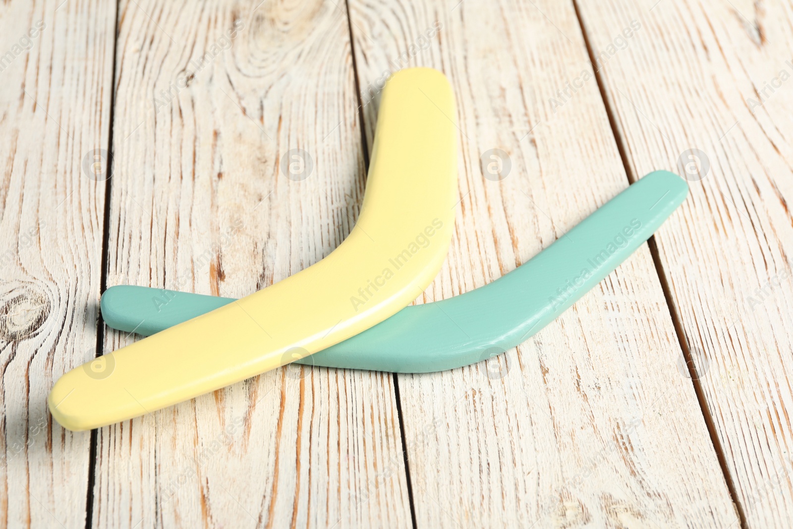 Photo of Color boomerangs on white wooden background. Outdoors activity