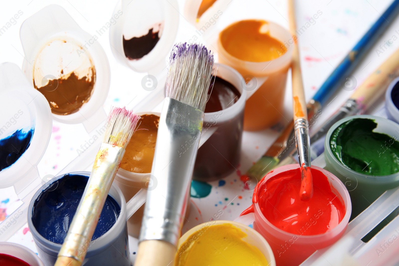 Photo of Jars with color paints and brushes on table, closeup