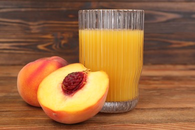Glass of delicious peach juice and fresh fruits on wooden table, closeup