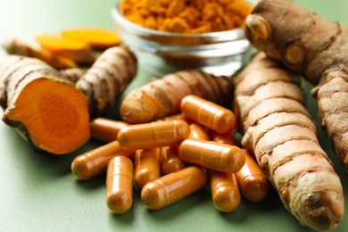 Photo of Turmeric roots and pills on green background, closeup