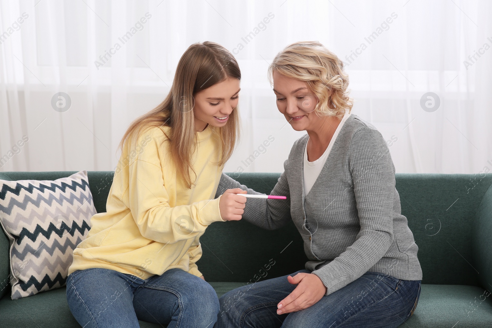 Photo of Young woman showing her mother pregnancy test at home. Grandparent reaction to future grandson