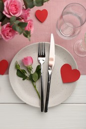 Photo of Romantic place setting with flowers and red paper hearts on white wooden table, flat lay. St. Valentine's day dinner