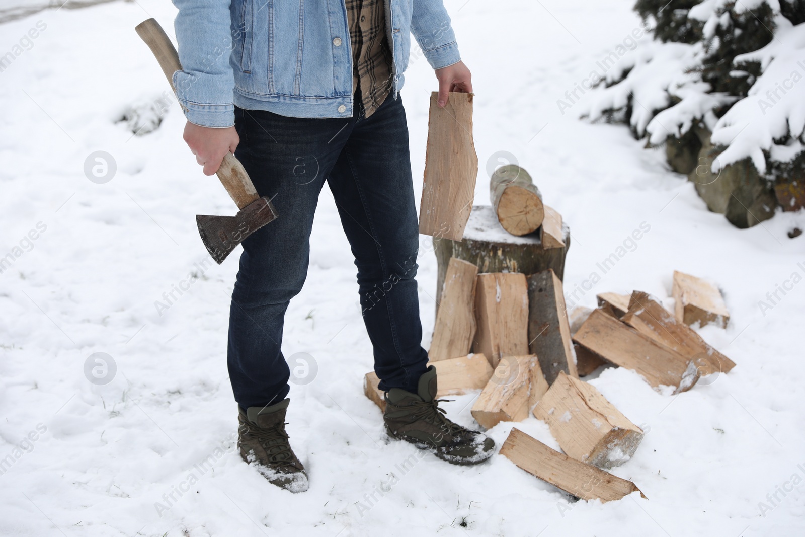 Photo of Man chopping wood with axe outdoors on winter day, closeup