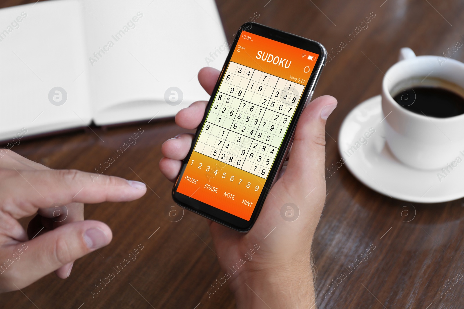 Image of Man playing sudoku game on smartphone indoors, closeup