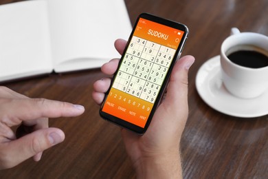 Man playing sudoku game on smartphone indoors, closeup