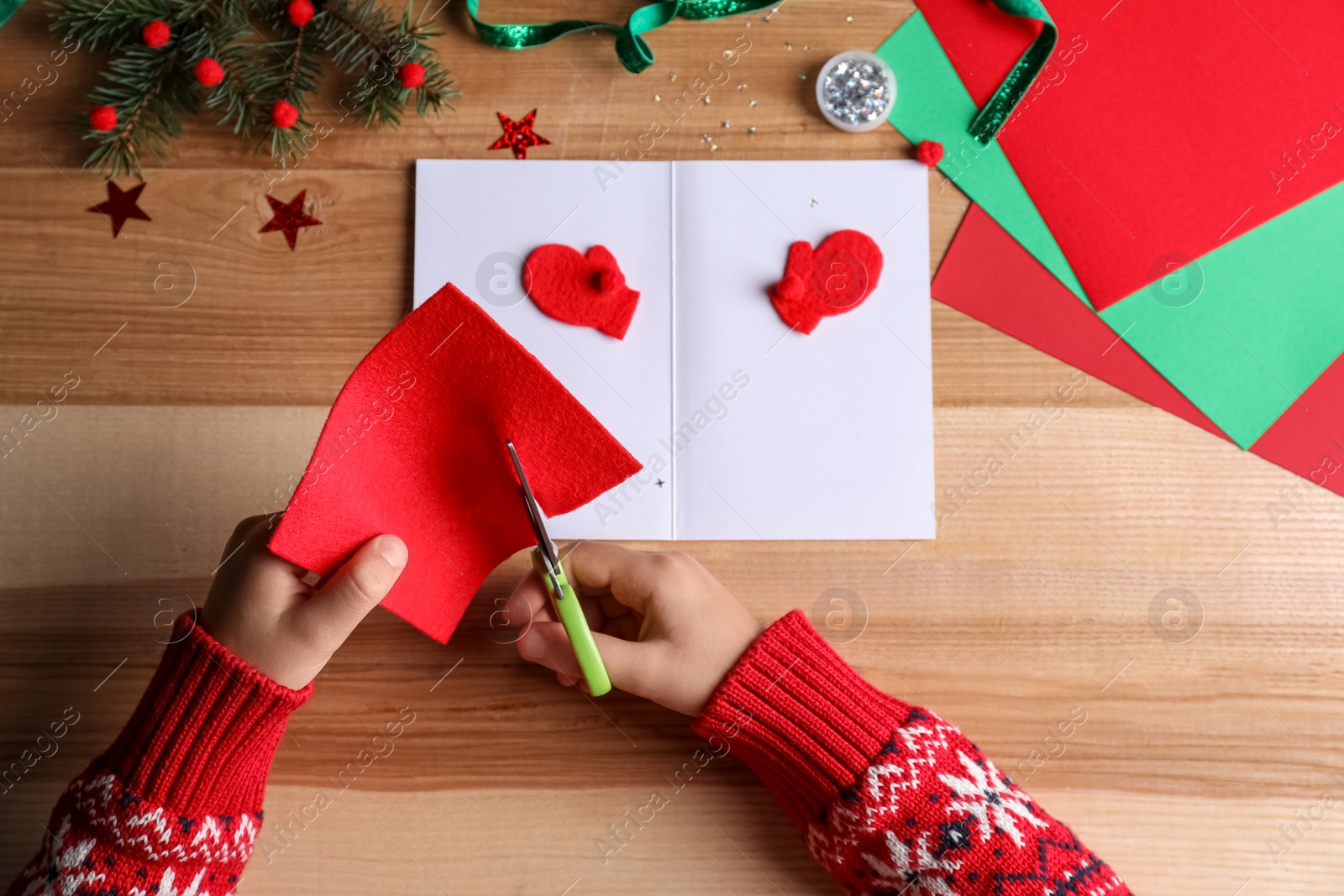 Photo of Little child making Christmas card at wooden table, top view