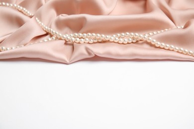 Beautiful pearls and pink silk on white background