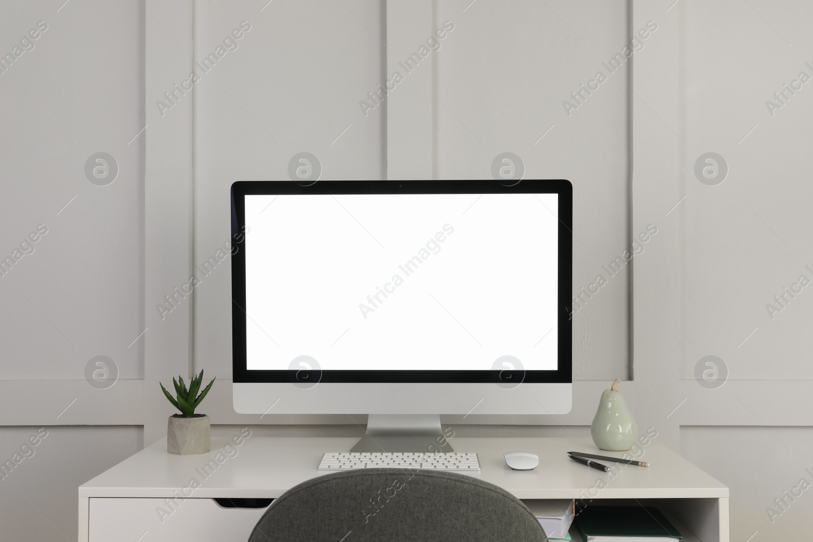 Photo of Modern computer, decor and office supplies on white wooden table near molding wall