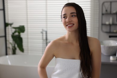 Photo of Smiling young woman after shower in bathroom. Space for text