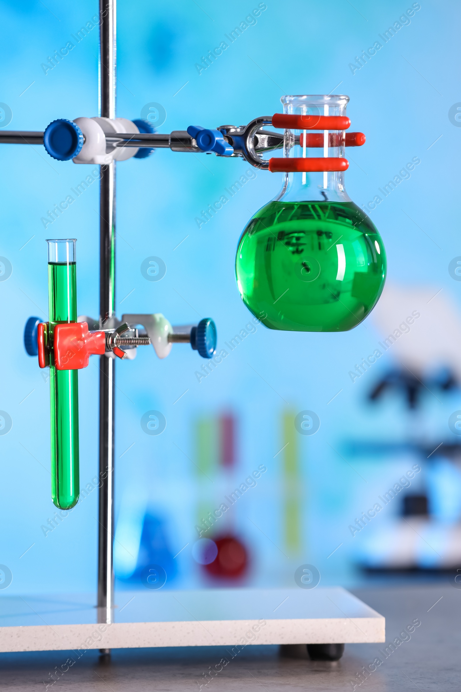 Photo of Laboratory glassware with green liquid on retort stand indoors