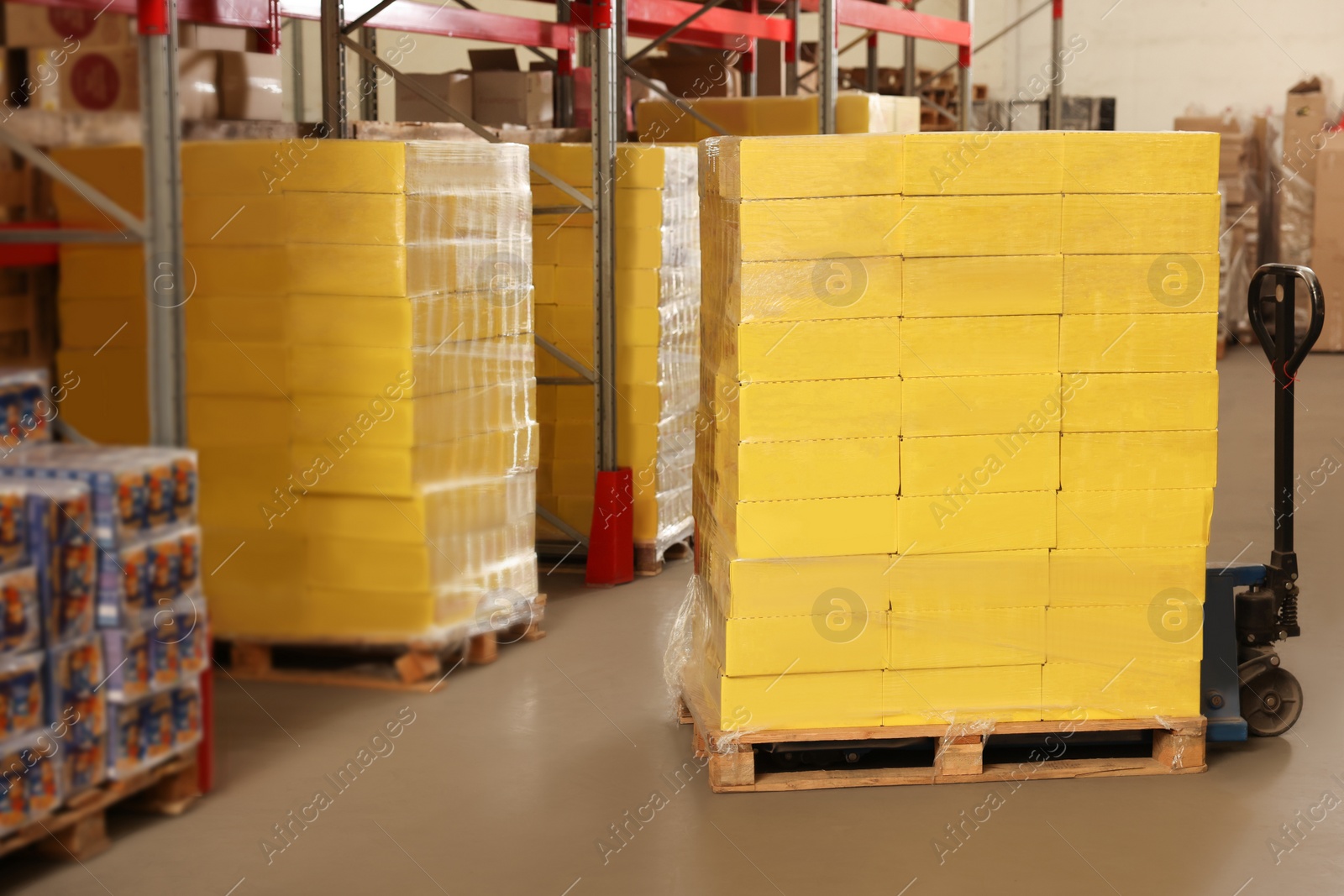 Photo of Manual pallet truck with stacked boxes in warehouse. Wholesaling