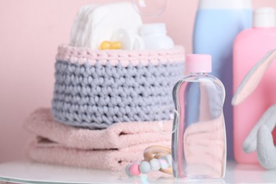 Photo of Baby cosmetic products, toys and accessories on white table against pink background