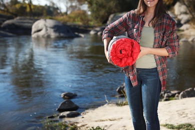 Photo of Female camper with sleeping bag near pond. Space for text