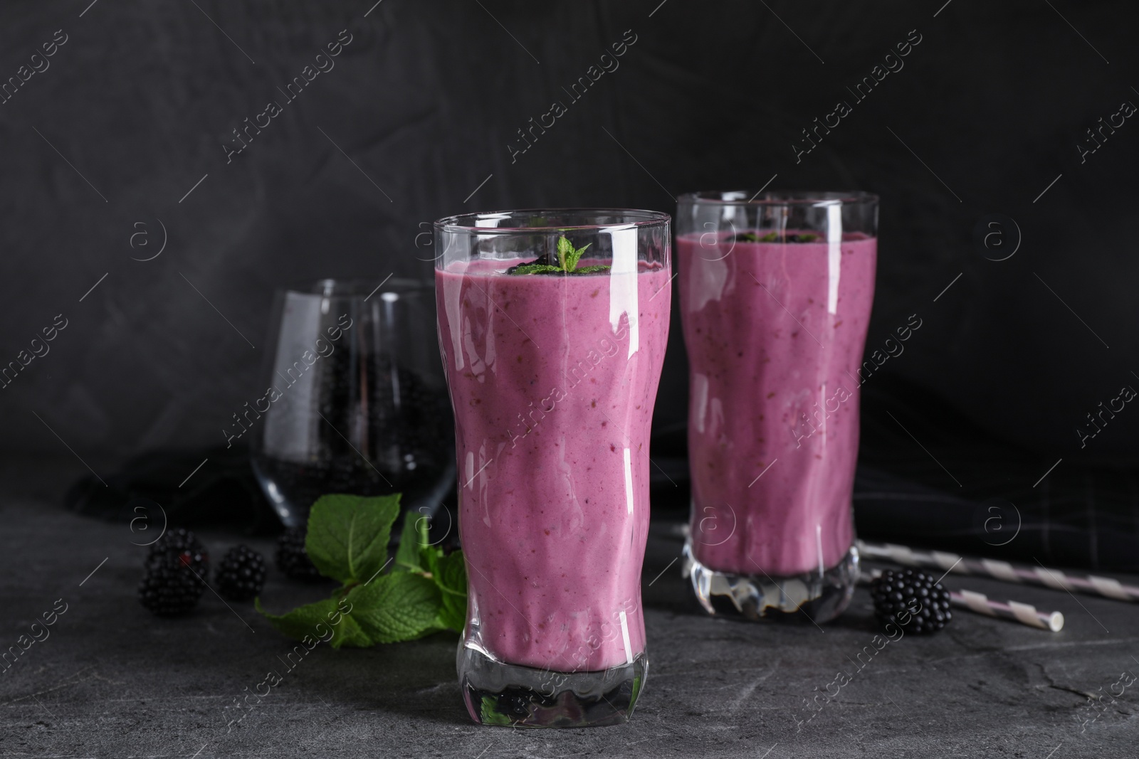 Photo of Glasses of tasty blackberry smoothie on grey table
