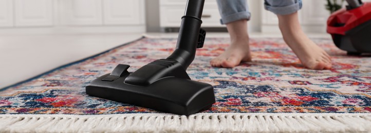 Woman cleaning carpet with vacuum cleaner at home, closeup. Banner design