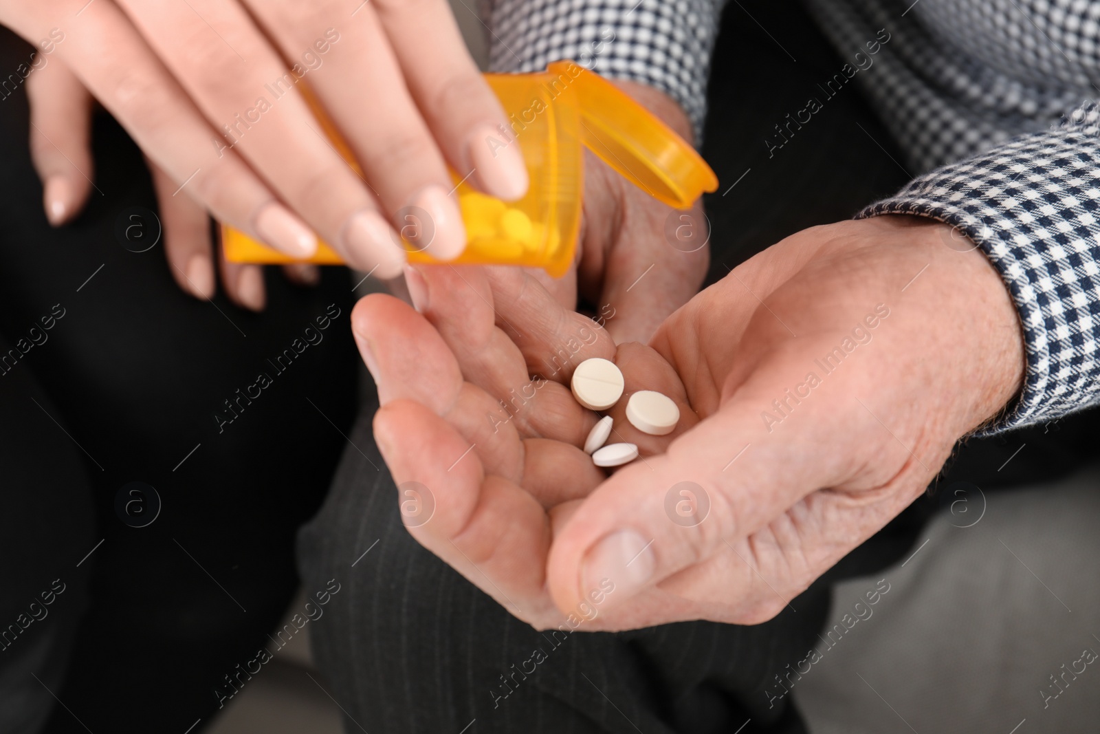 Photo of Woman giving pills to senior man, closeup