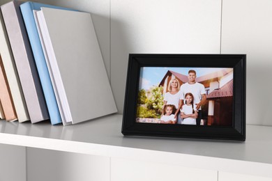 Photo of Frame with family photo and books on shelf indoors