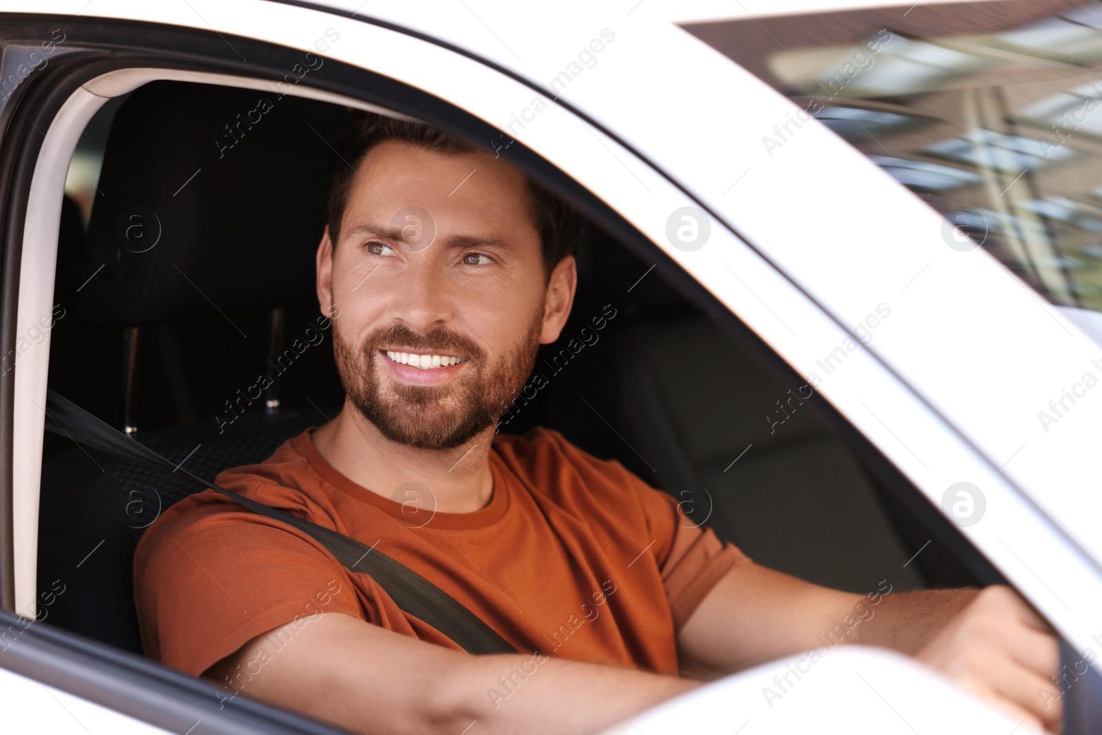 Photo of Enjoying trip. Happy bearded man driving his car, view from outside